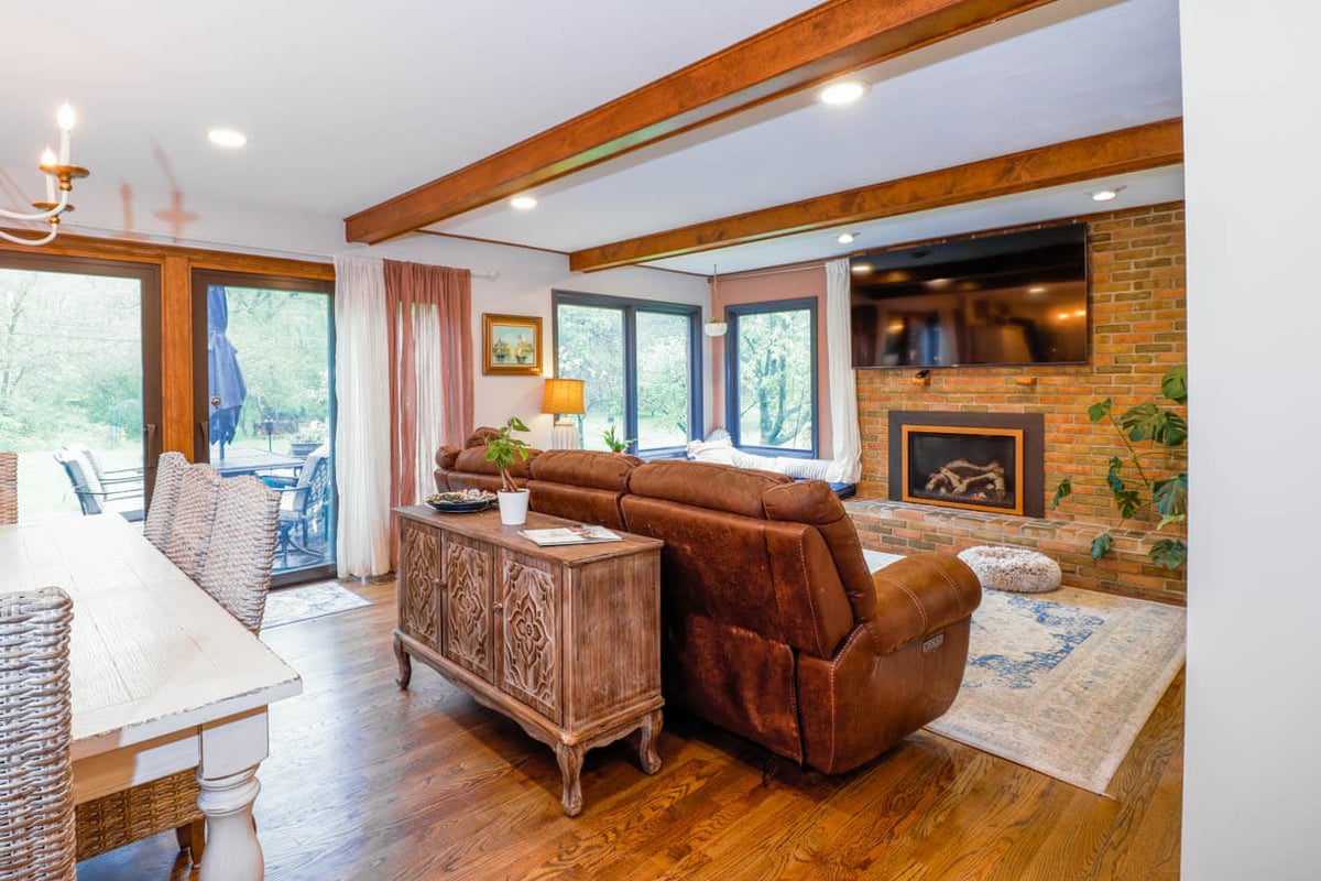 Living room remodel in a Tacoma Hills, MI custom home by Odd Fellows Contracting featuring brick fireplace and wood beams.