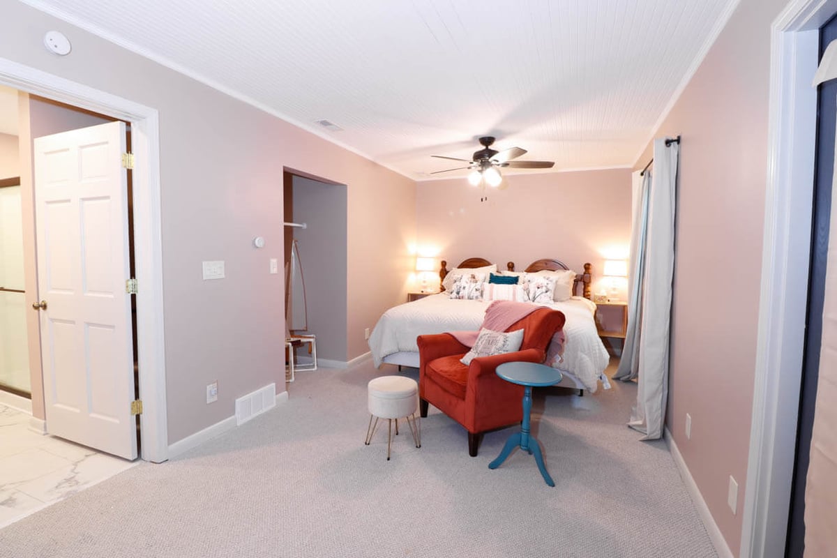 Primary bedroom remodel in a Tacoma Hills, MI custom home by Odd Fellows Contracting featuring soft pink walls and updated lighting.