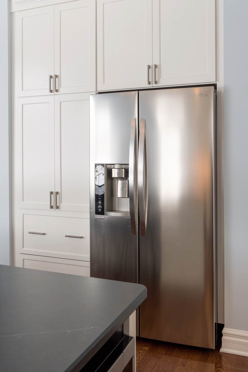 Built in refrigerator surrounded by white cabinets in Bath Township kitchen remodel by Odd Fellows Contracting