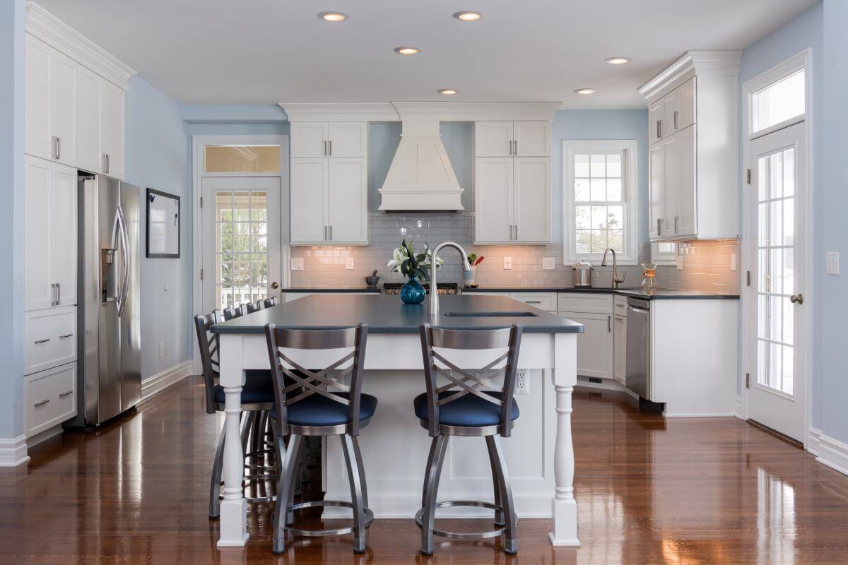 Modern kitchen layout with island and recessed lighting in Williamston MI by Odd Fellows Contracting
