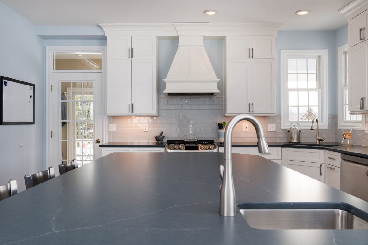 Quartz kitchen island countertop with modern faucet in Bath Township remodel by Odd Fellows Contracting Williamston MI