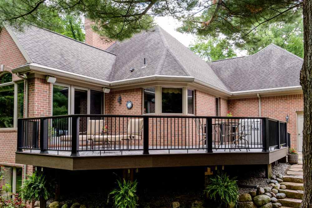 Large composite backyard deck with metal railing in Williamston MI built by Odd Fellows Contracting