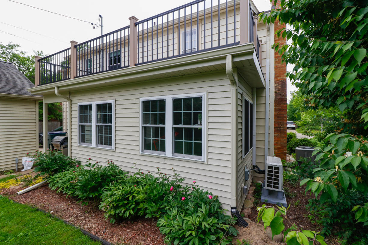 Side view of sunroom addition by Odd Fellows Contracting in Orchard-Street, MI with elevated deck and HVAC unit.