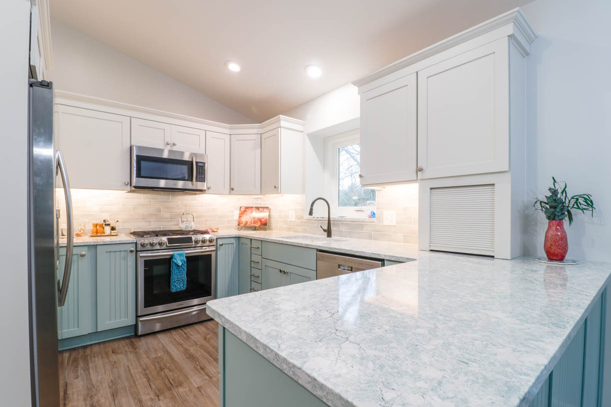 Close-up of quartz countertop and beadboard peninsula from kitchen remodel by Odd Fellows Contracting in Williamston, MI